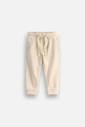 MOKIDA WEAR MOKIDA WEAR Spodnie dresowe niemowlęce SLIM FIT beżowe gładkie z wiązaniem w pasie o fasonie REGULAR rozmiar 98 dla chłopca